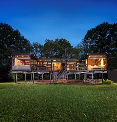 House on stilts with rooms lit at dusk