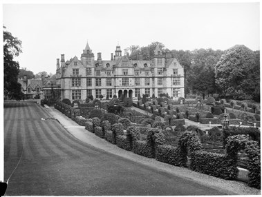 archive black and white photograph of a large country house with formal gardens in the foreground