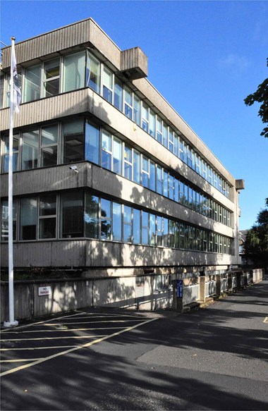 Three-storey concrete building with a continuous line of windows